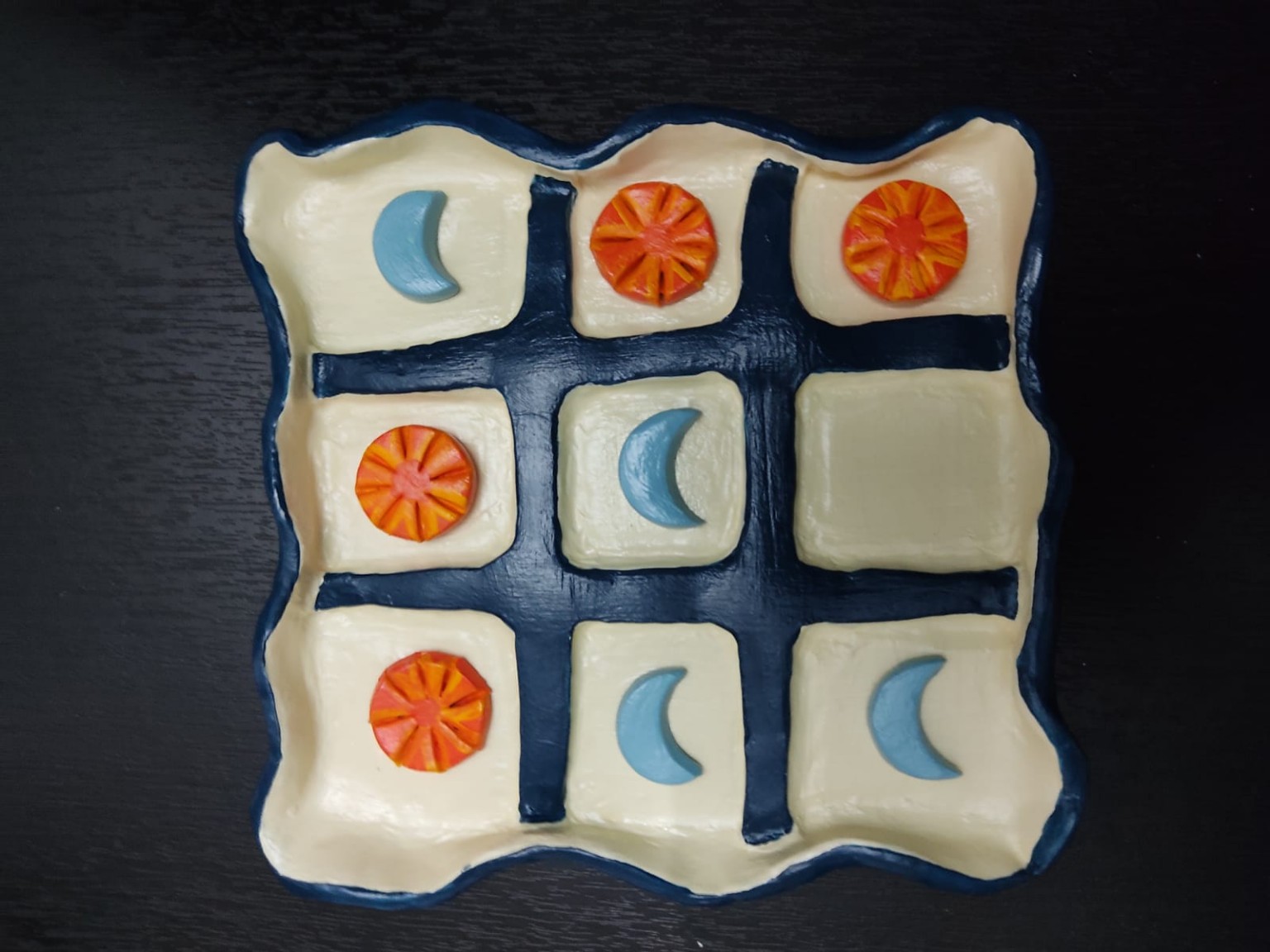 Triqui terminado con fichas de lunas azules y soles naranjas