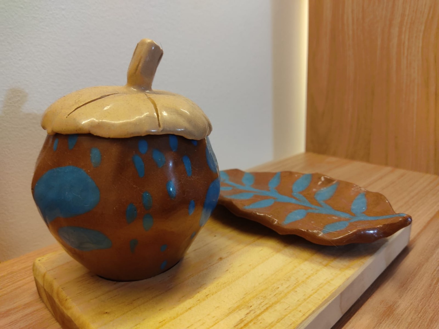 Fruta del otro mundo terminada junto a la hoja de cerámica, con terracota, tapa natural y detalles de engobe azul
