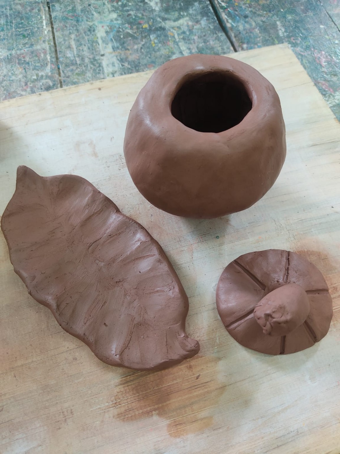 Fruta, tapa y hoja antes de la cocción, modeladas a mano en arcilla