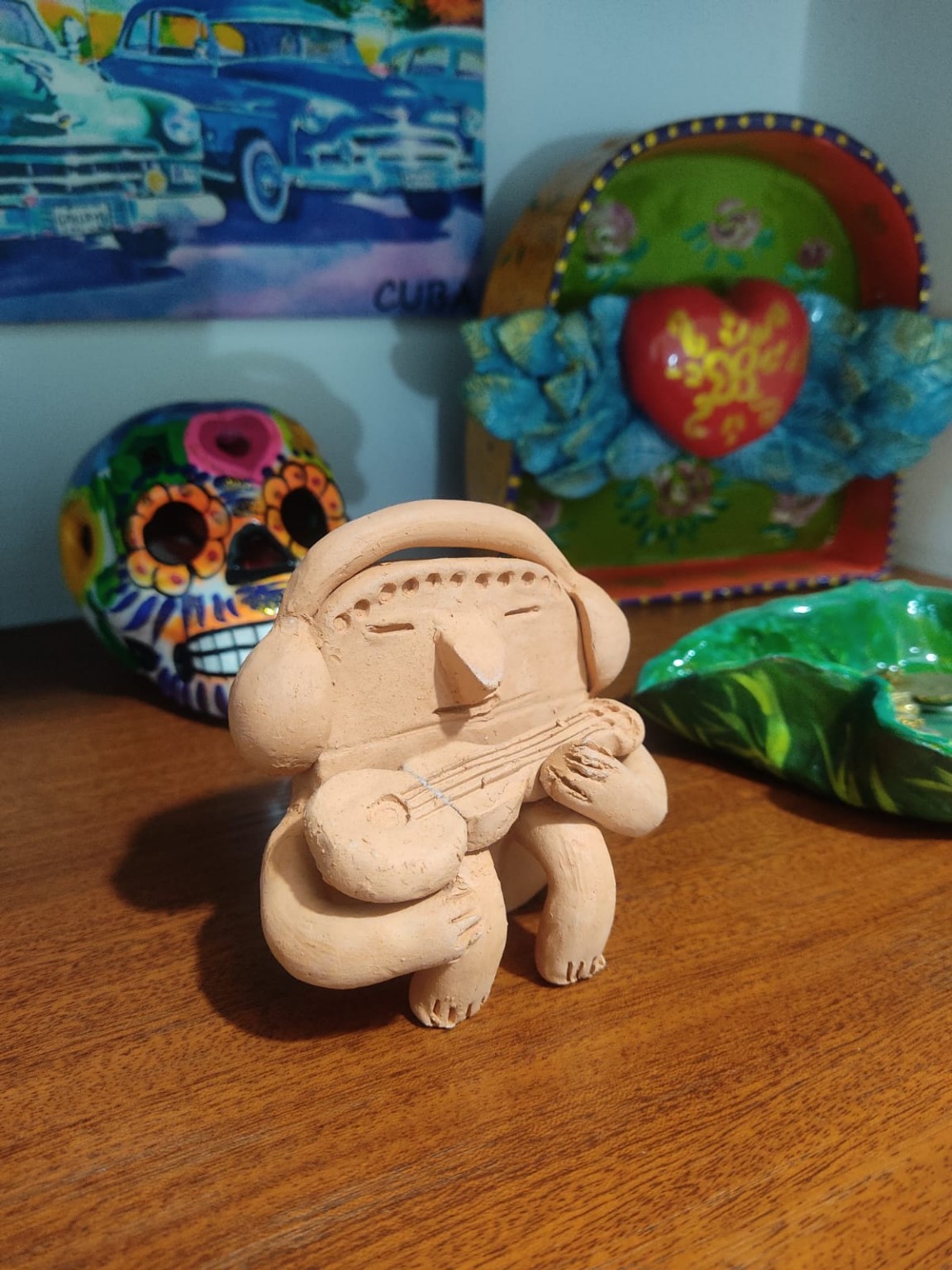 Figura de inspiración precolombina con audífonos y un instrumento musical